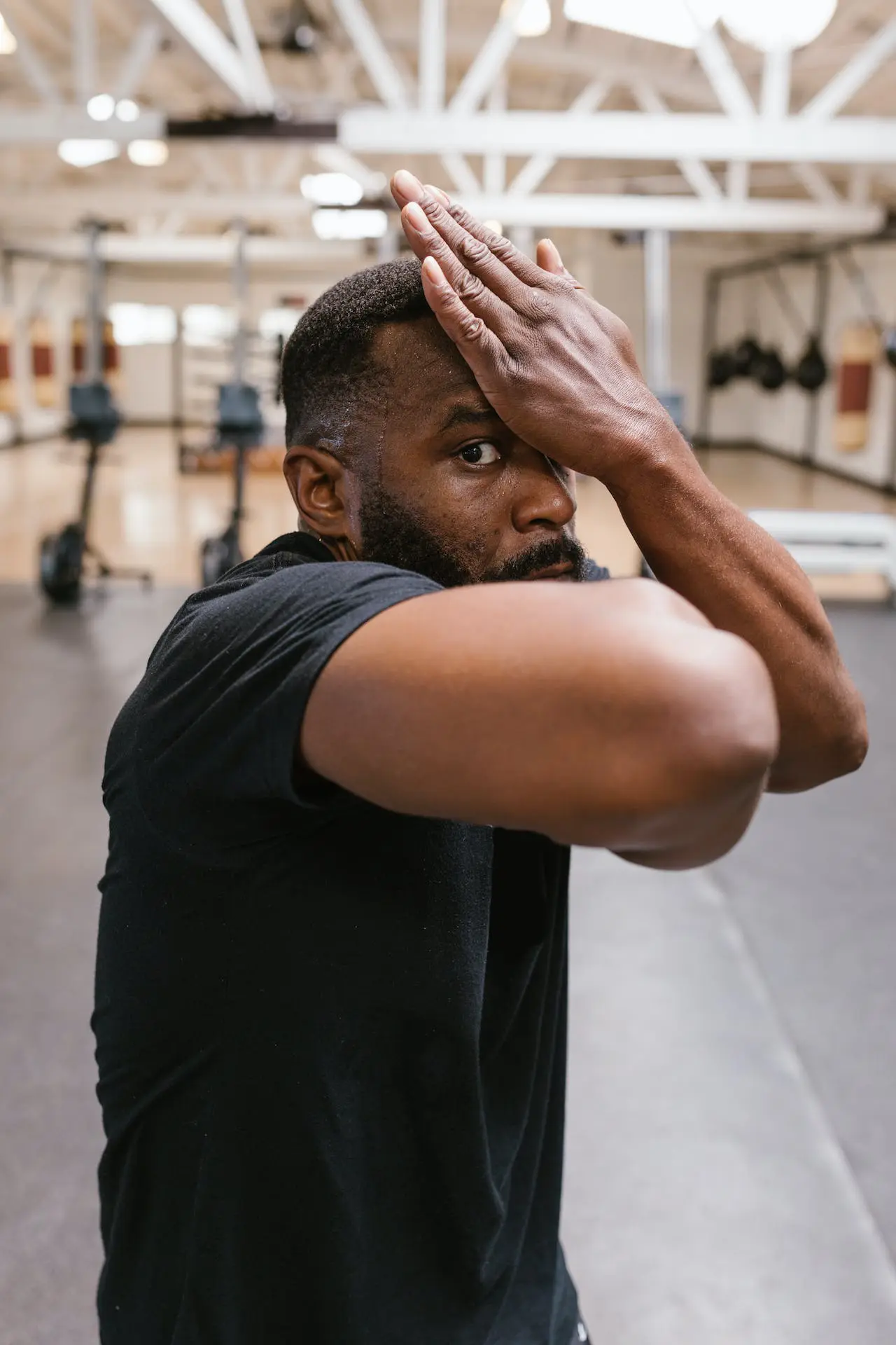 homme en tenue de sport effectuant un étirement dans une salle de combat