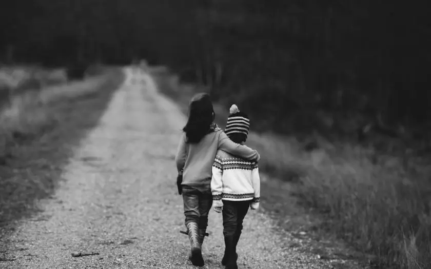 deux enfants marchant sur une route de campagne en noir et blanc