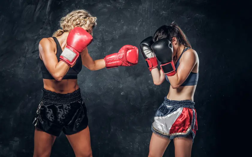 deux femmes en tenue de muay thai avec shorts et gants de boxe rouges