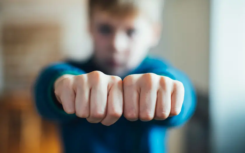 enfant en tenue de boxe montrant ses poings fermés vers la caméra