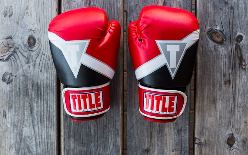 pair of red-and-black Title training gloves on grey wooden plank