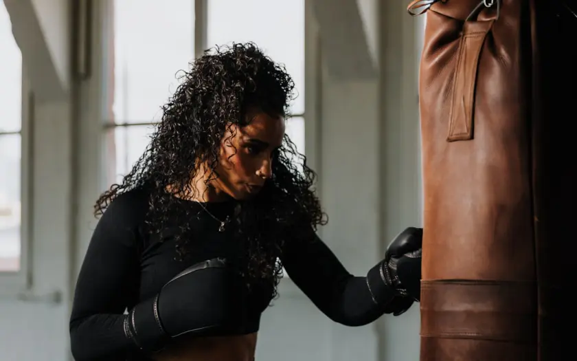 a woman in a black top and black gloves near a punching bag